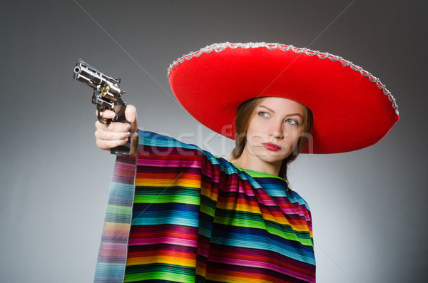 Girl in mexican vivid poncho holding handgun against gray Stock photo © Elnur
