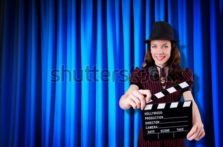 Stock photo: Girl with movie board against curtains