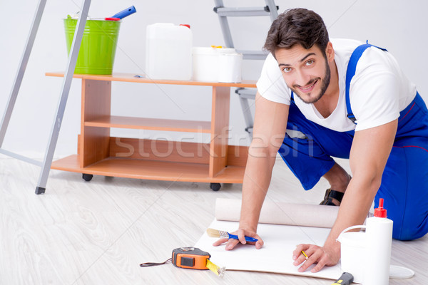 Stock photo: Repairman doing renovation repair in the house with paper wallpa