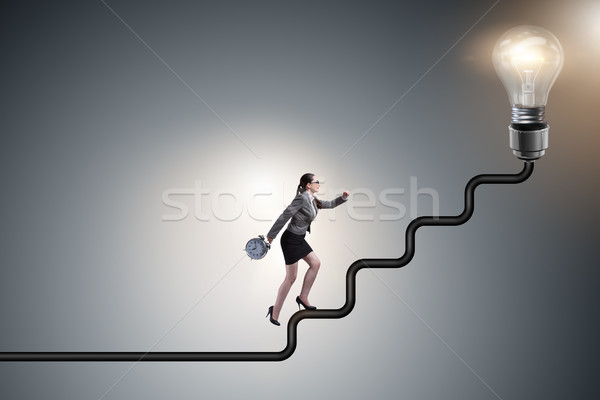 Businesswoman climbing career ladder towards light bulb Stock photo © Elnur