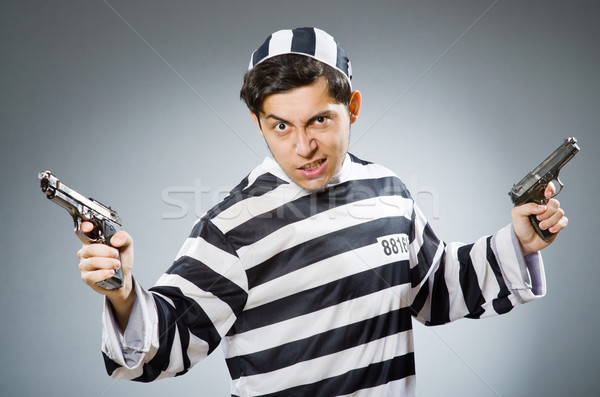 Stock photo: Prisoner with gun against dark background