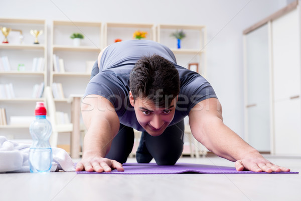 Young man exercising at home in sports and healthy lifestyle con Stock photo © Elnur