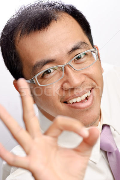 Businessman of Asian showing OK gesture and smiling. Stock photo © elwynn