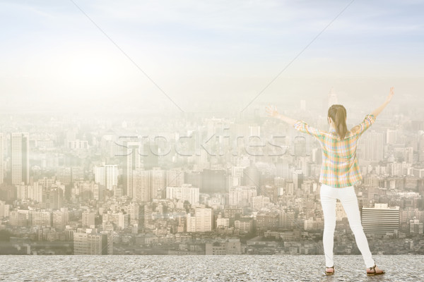 Stock photo: Young woman with stretched arms looking at city