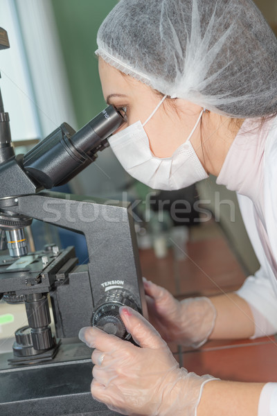 Woman scientist looking in a microscope Stock photo © Epitavi