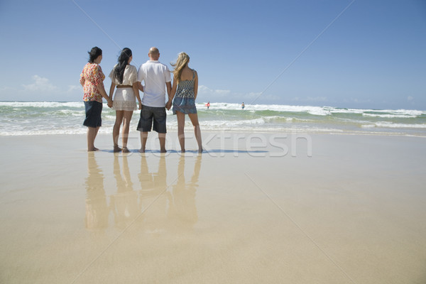 family holding hands looking out to surf Stock photo © epstock