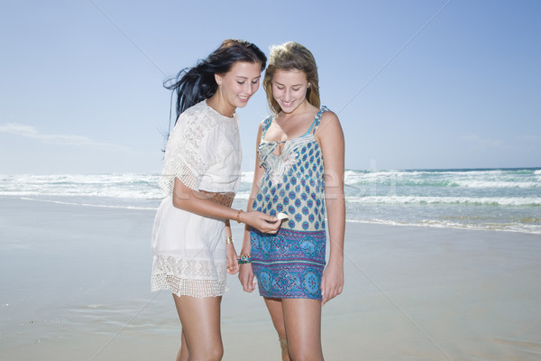 sisters looking at shell on beach Stock photo © epstock