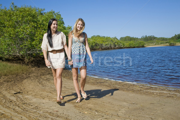 two girls holding hands walking and giggeling by the creek Stock photo © epstock