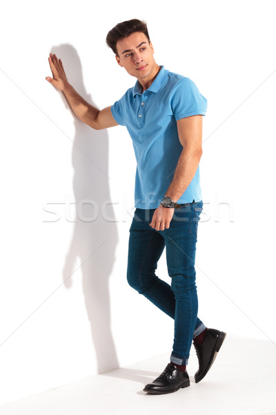 casual man in blue polo shirt, leaning against studio wall Stock photo © feedough