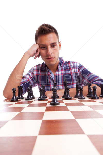 Stock photo: Young casual man thinking in front of the chessboard