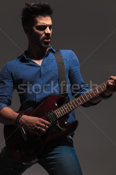 Pasionat tineri ghitarist joc chitara electrica gri Imagine de stoc © feedough