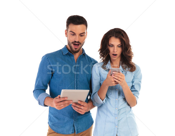 amazed casual couple reading surprising things on their mobile d Stock photo © feedough