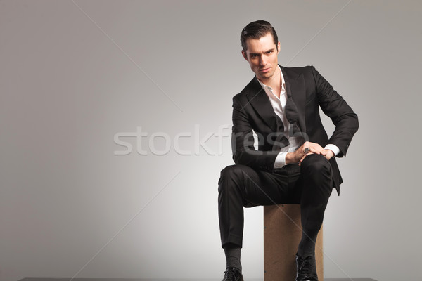 elegant man sitting on wooden box with undone bowtie Stock photo © feedough