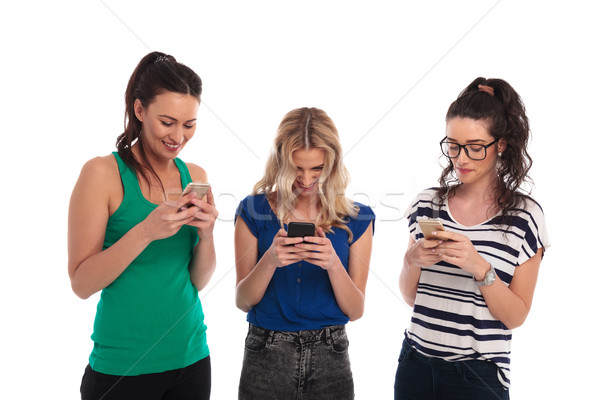 Risonho mulheres jovens leitura mensagens de texto telefones branco Foto stock © feedough