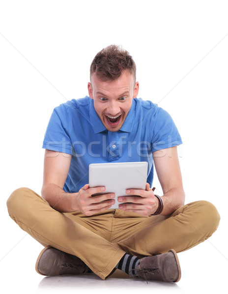 seated young man shocked by his tablet Stock photo © feedough