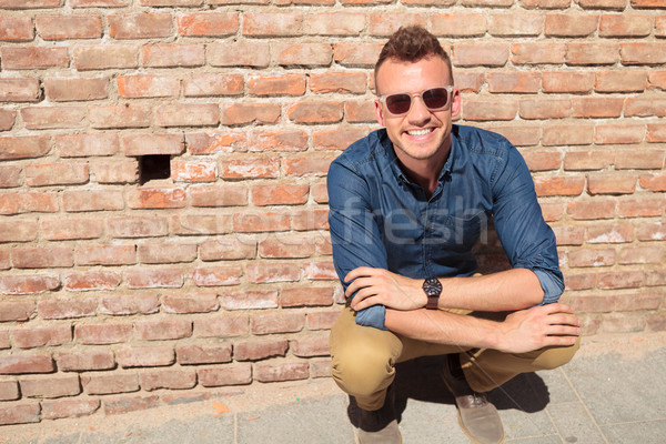 casual man crouches in front of brick wall Stock photo © feedough