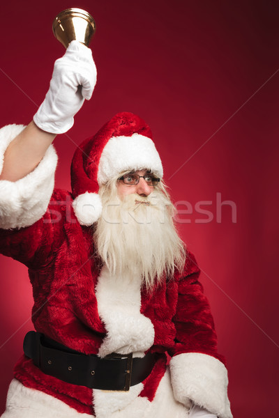 seated santa claus rings his bell and looks to side Stock photo © feedough