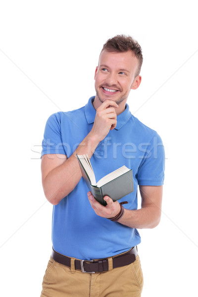 young casual man holds book and smiles pensively Stock photo © feedough