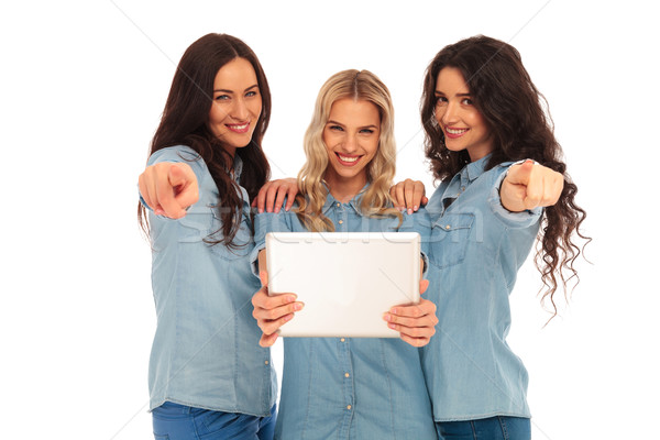 three casual women holding a tablet are pointing fingers Stock photo © feedough