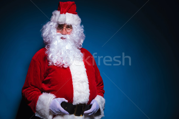Santa looking at the camera while holding his belt. Stock photo © feedough