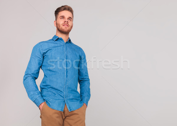 attractive man with hands in pockets looks up to side Stock photo © feedough