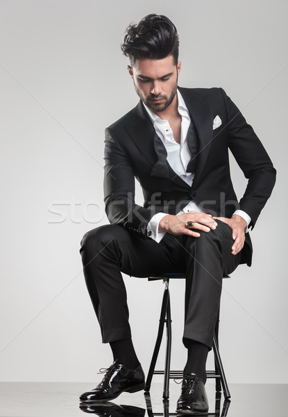 Elegant young man stitting on a stool while looking down Stock photo © feedough