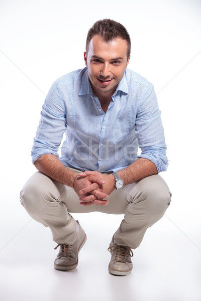 casual man sitting crouched and smiling Stock photo © feedough