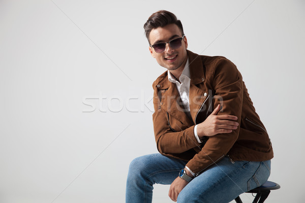 Uśmiechnięty moda człowiek posiedzenia łokieć szary Zdjęcia stock © feedough