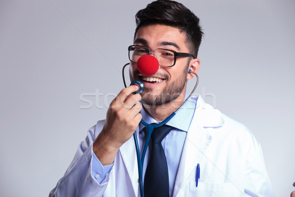 young doctor with clown red nose listens to himself Stock photo © feedough
