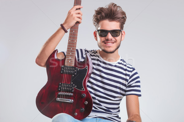 Stock photo: rocker posing in studio with electric guitar in his lap