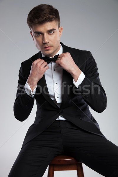 seated handsome man in black tuxedo fixing his bowtie Stock photo © feedough