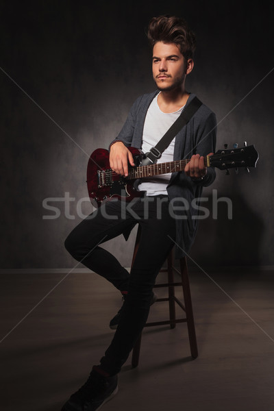 skinny rocker playing guitar while sitting and looking away Stock photo © feedough