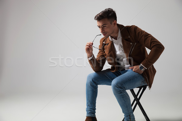 pensive young fashion man sitting and holding sunglasses Stock photo © feedough