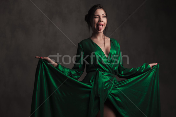 joyful woman holding her green gown makes a crazy face Stock photo © feedough