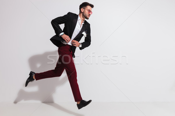 side view of elegant man running and buttoning his suit Stock photo © feedough