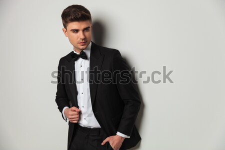 sexy young man in tuxedo and bowtie buttoning his suit Stock photo © feedough