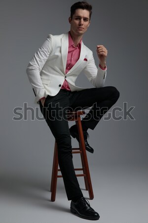 Stock photo: business man sitting on a stool while fixing his beard