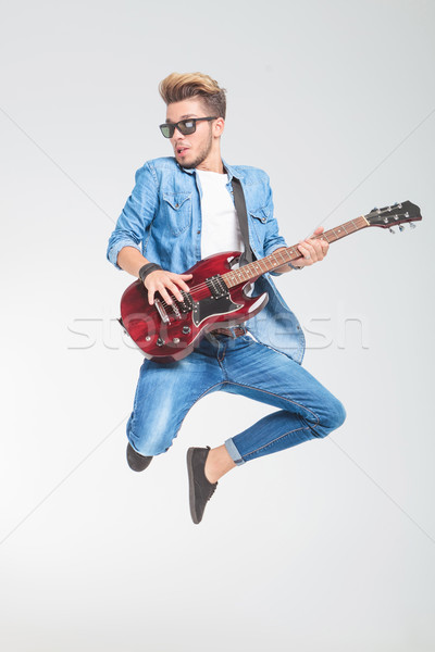guy wearing sunglasses jumping in studio while playing guitar Stock photo © feedough