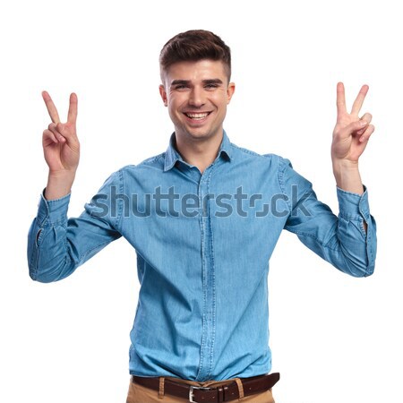 Stock photo: seated casual man making the victory sign and smiles 