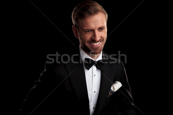 laughing young man in tuxedo and bowtie looks down Stock photo © feedough