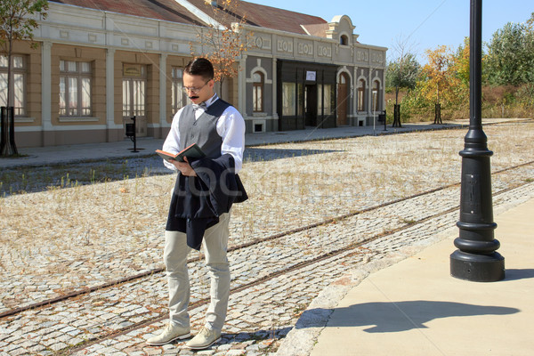 Man with mustache walking along the rails reading book Stock photo © feelphotoart
