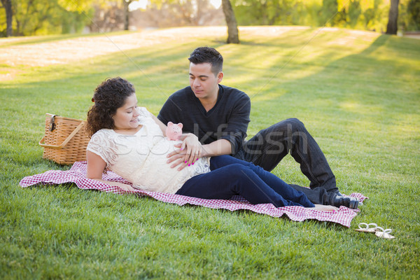 Pregnant Hispanic Couple with Piggy Bank on Belly in Park Stock photo © feverpitch