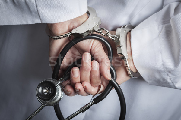 Stock photo: Female Doctor or Nurse In Handcuffs Holding Stethoscope