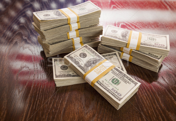 Stock photo: Thousands of Dollars with Reflection of American Flag on Table