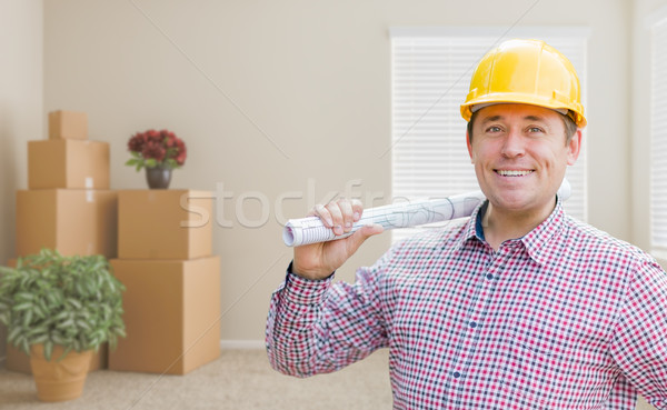 Male Construction Worker In Room With Boxes Holding Roll of Blue Stock photo © feverpitch