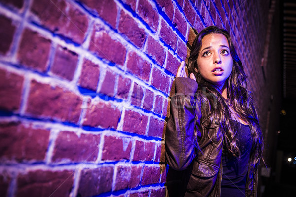 Frightened Pretty Young Woman Against Brick Wall at Night Stock photo © feverpitch