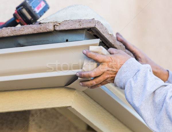 Worker Attaching Aluminum Rain Gutter to Fascia of House. Stock photo © feverpitch