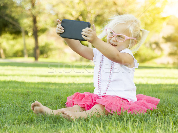 Stock photo: Little Girl In Grass Taking Selfie With Cell Phone
