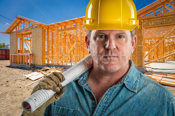 Serious Contractor in Hard Hat Holding Floor Plans At Constructi Stock photo © feverpitch