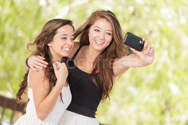 Two Attractive Mixed Race Girlfriends Using Their Smart Cell Pho Stock photo © feverpitch
